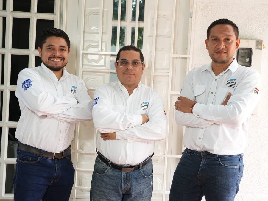 Tres colaboradores de SICMAR con la dotación de la empresa en la entrada de la sede